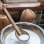 spoon lifting coconut milk from a bowl.