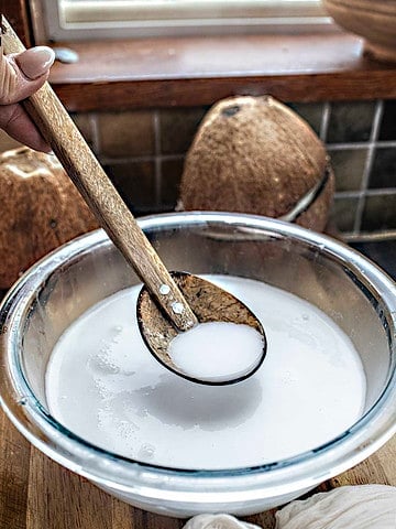 spoon lifting coconut milk from a bowl.