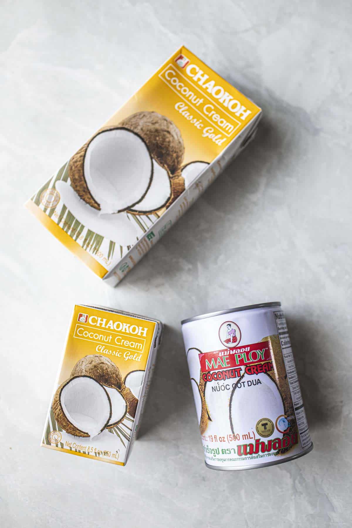 Coconut cream in a can and 2 cartons   on a table. 