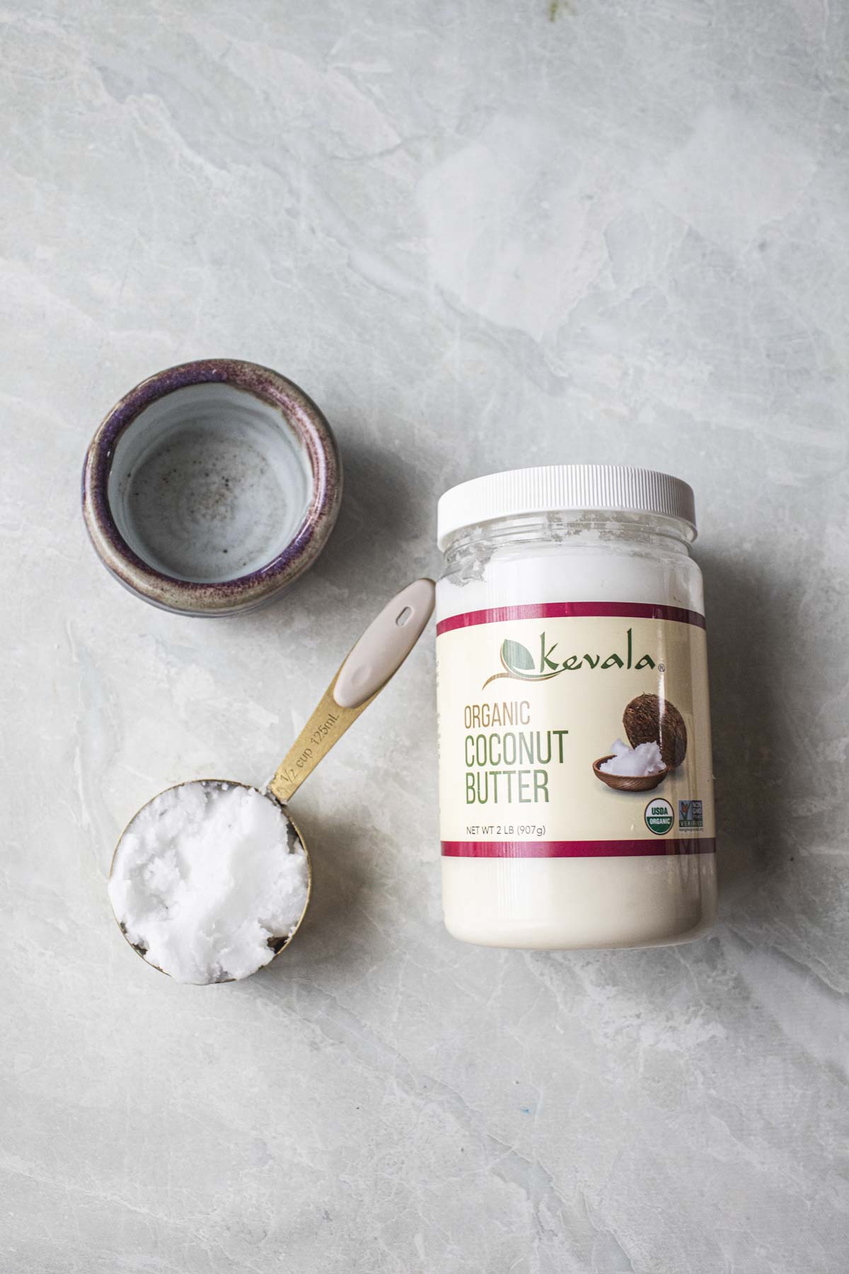 Coconut butter in a jar and measuring cup on a table. 