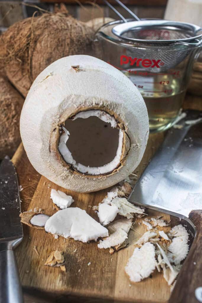 An opening in a young coconut on a cutting board.