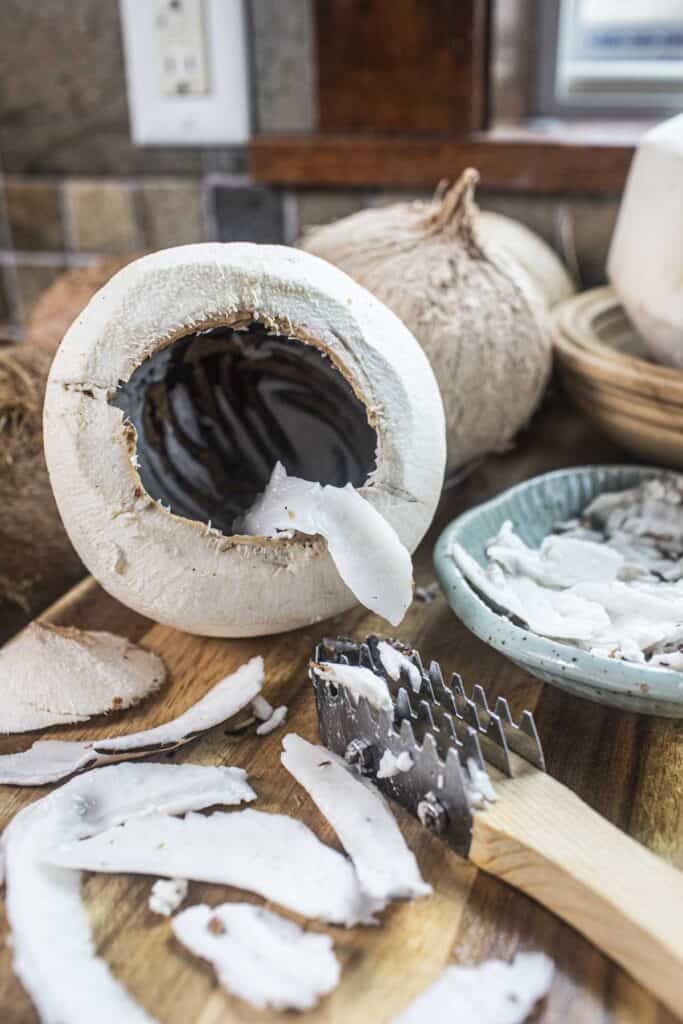 Coconut meat in a young coconut on a cutting board.