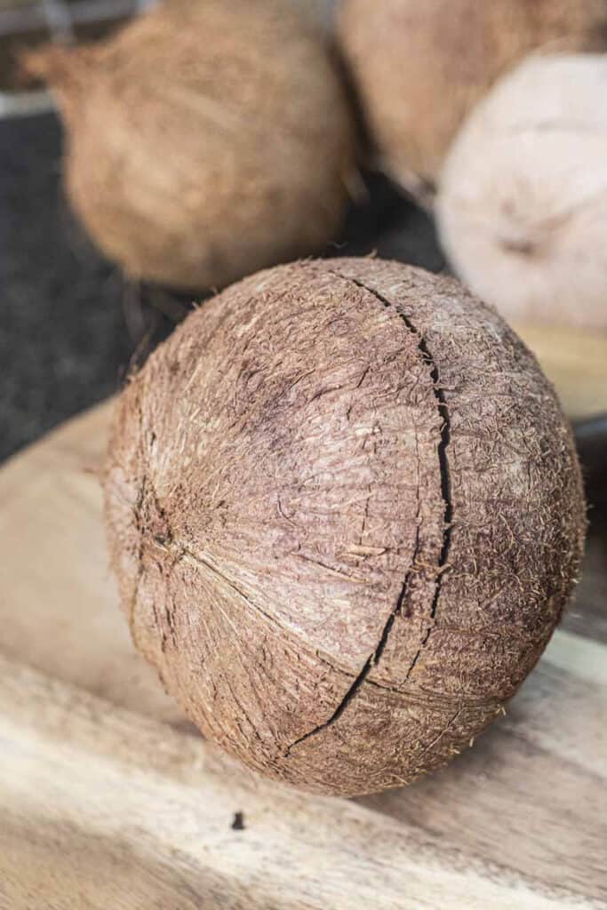 Cracked whole coconut on a cutting board.