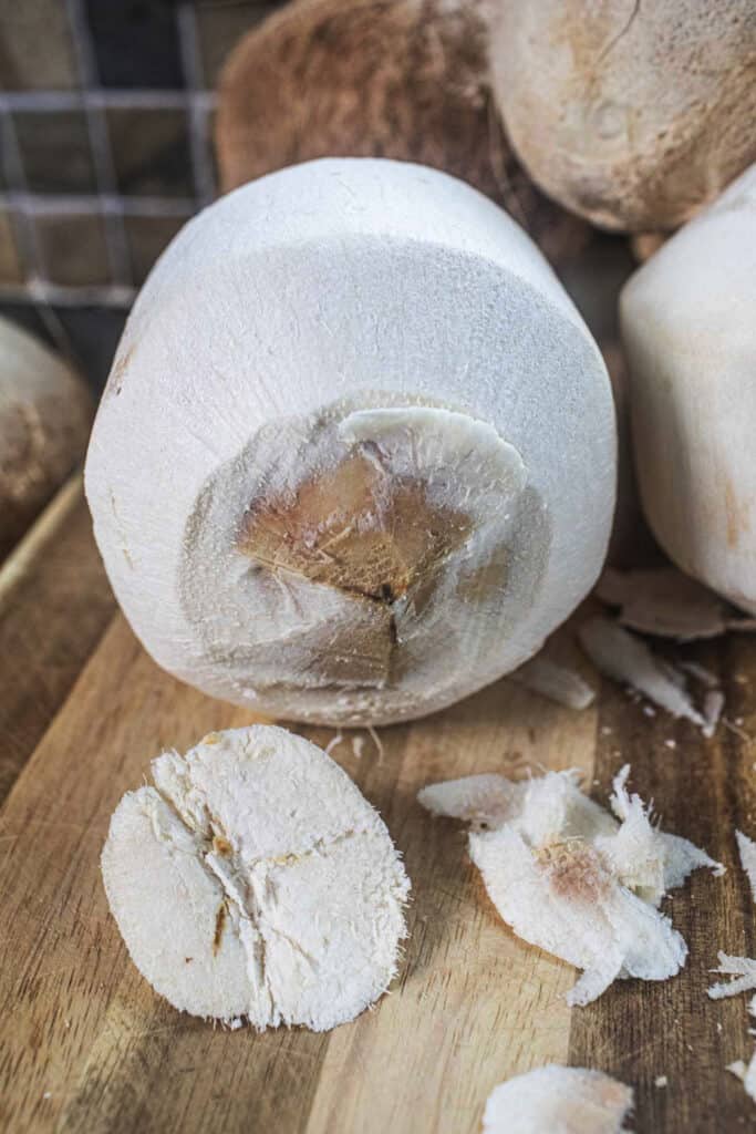 Shaved pieces from Top of a young coconut on a cutting board.