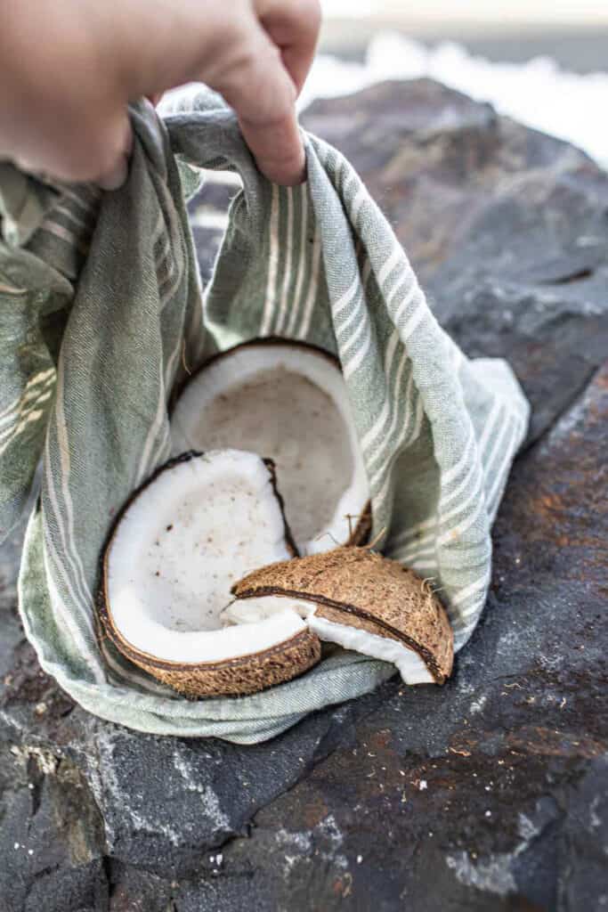 A towel wrapped around a cracked coconut on a rock. 