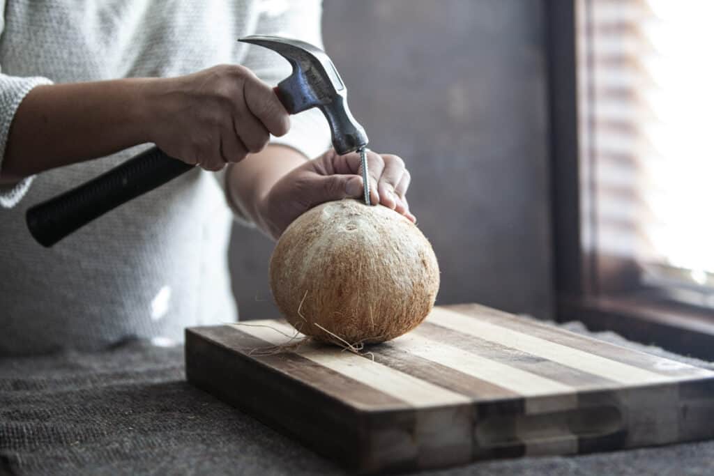 A hammer on a screw nail on a cutting board.