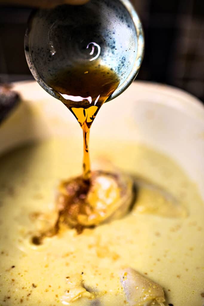 Sauce pouring into a pot of Kao Soi curry broth. 