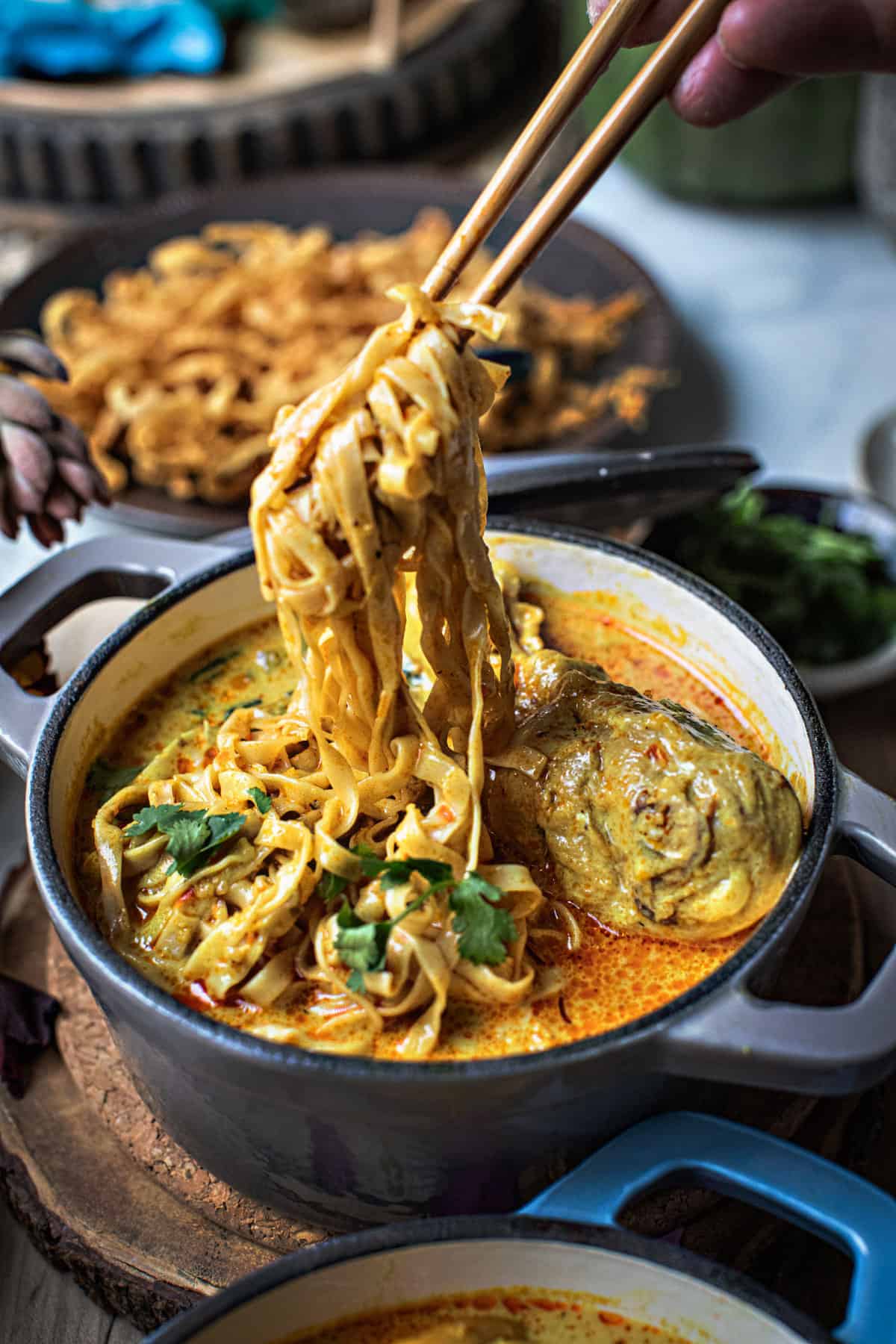 Chop sticks lifting chiang mai noodles soup from a bowl.