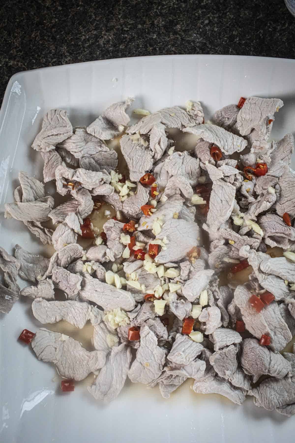 Pork slices with garlic and choped chilis on top.