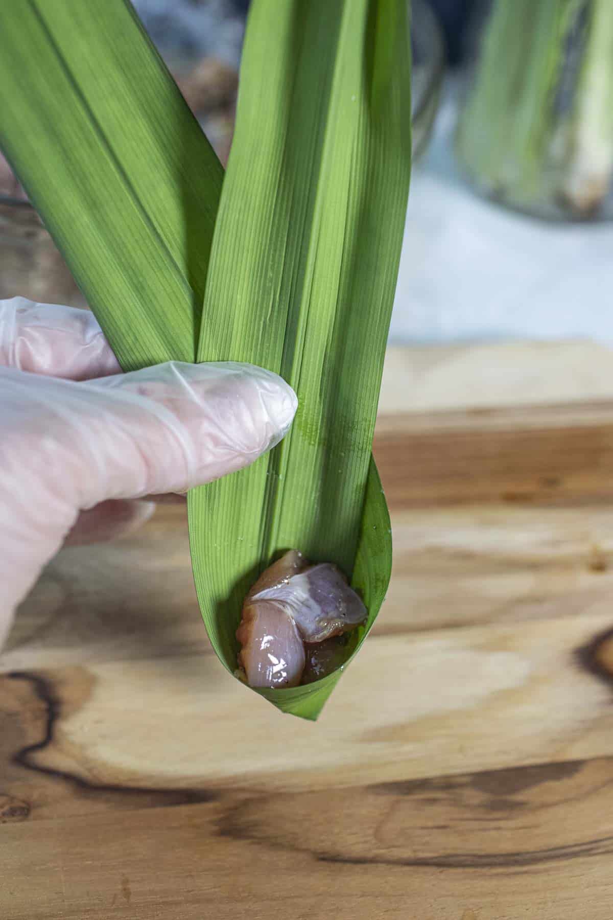 Chicken meat in a ribboned shaped pandan leaf.