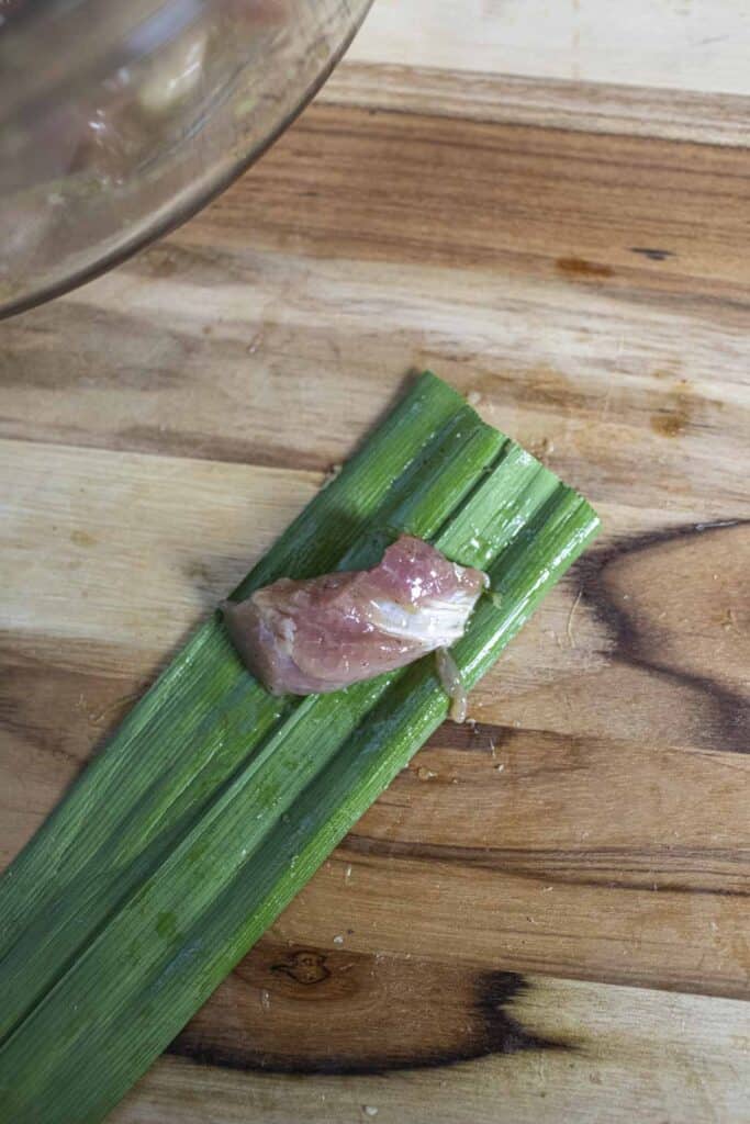 Chicken meat onto of a pandan leave  on a cutting board. 