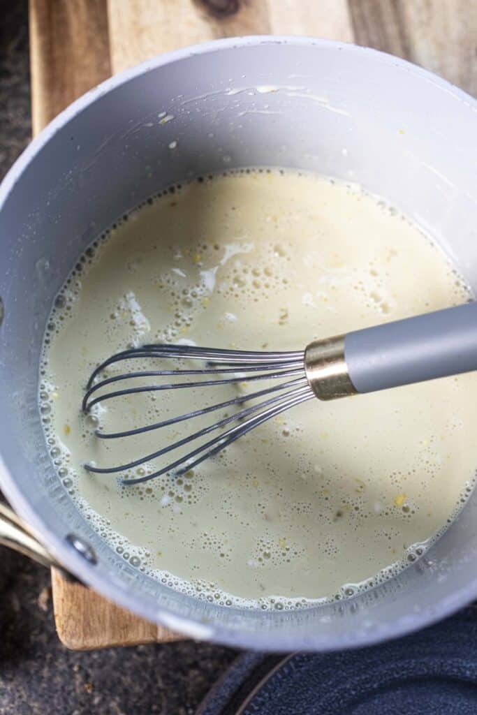 Egg and milk mixture in a pot with a whisk.