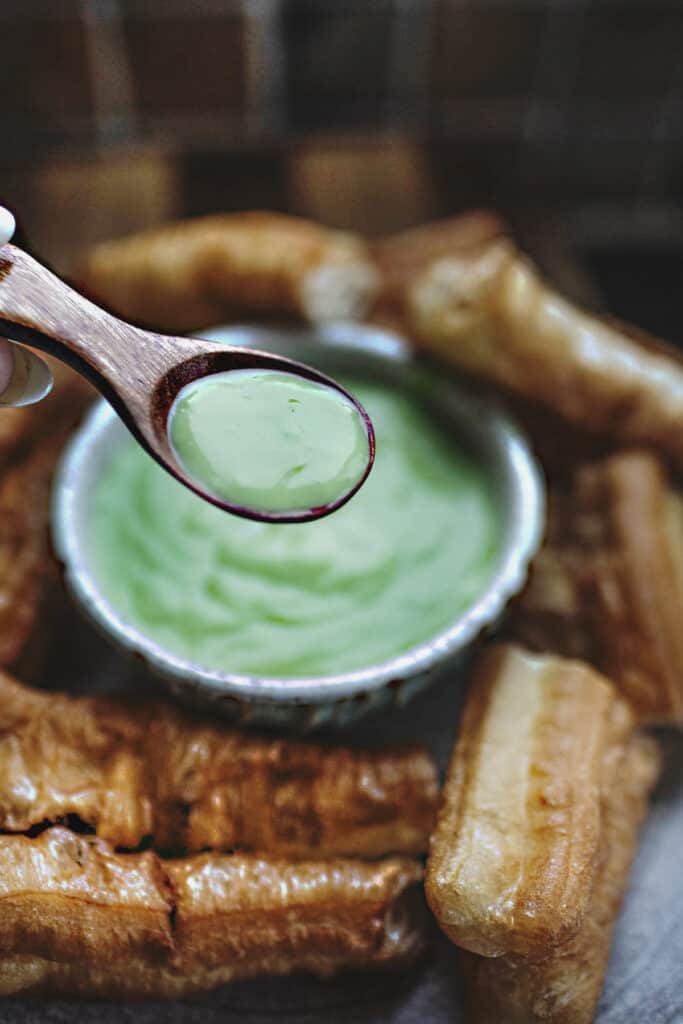 a spoon lifting Thai green pandan custard dessert.