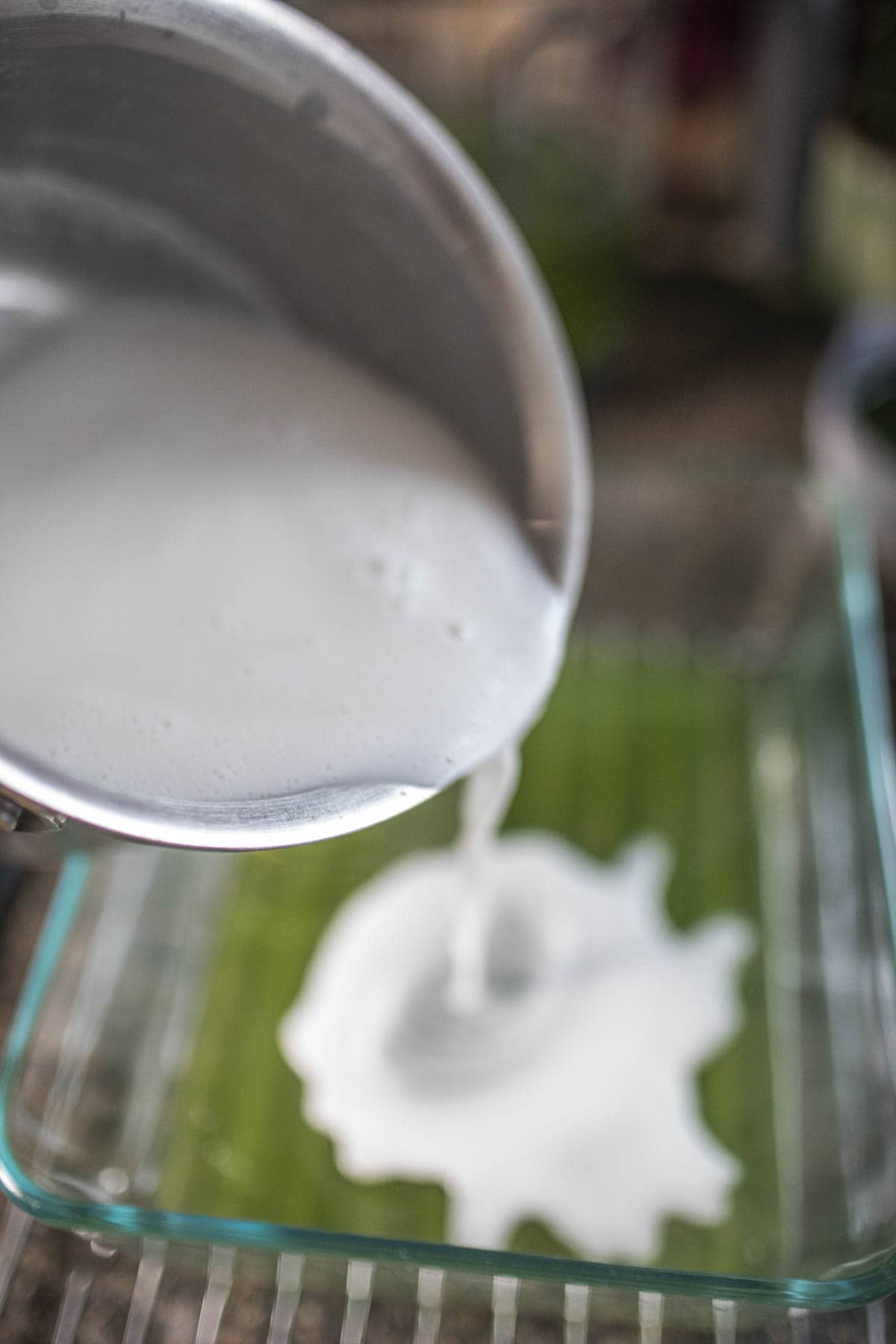 Coconut milk pouring into a glass with pandan jelly.