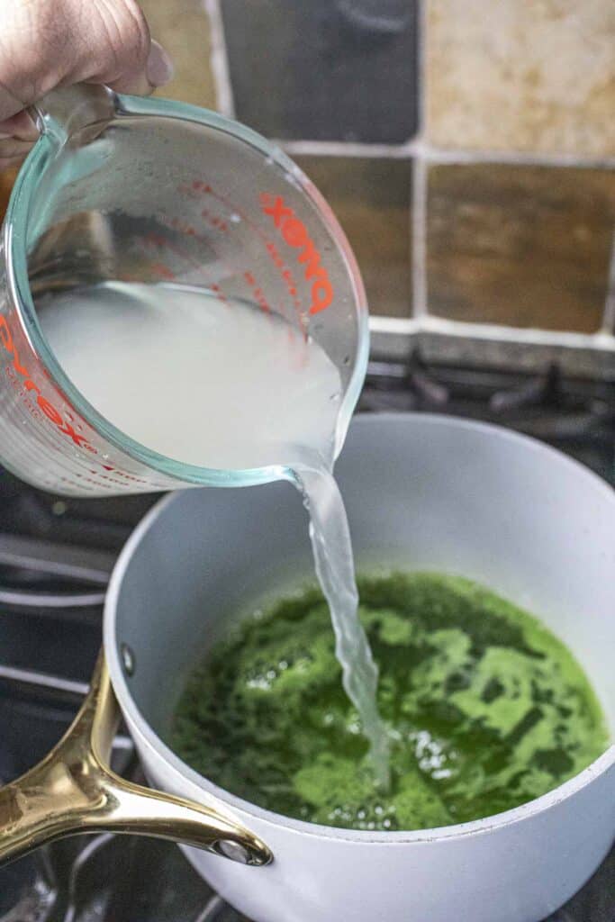 Agar solution pouring into a pot with green pandan water. 