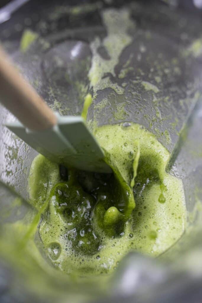 A spatula inside a food processor with pandan mixture.