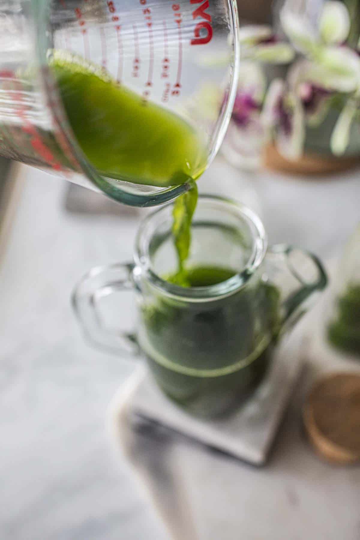 Green pandan liquid pouring into a glass vase. 
