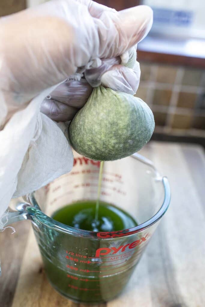 Cheese cloth draining pandan liquid into a measuring cup.