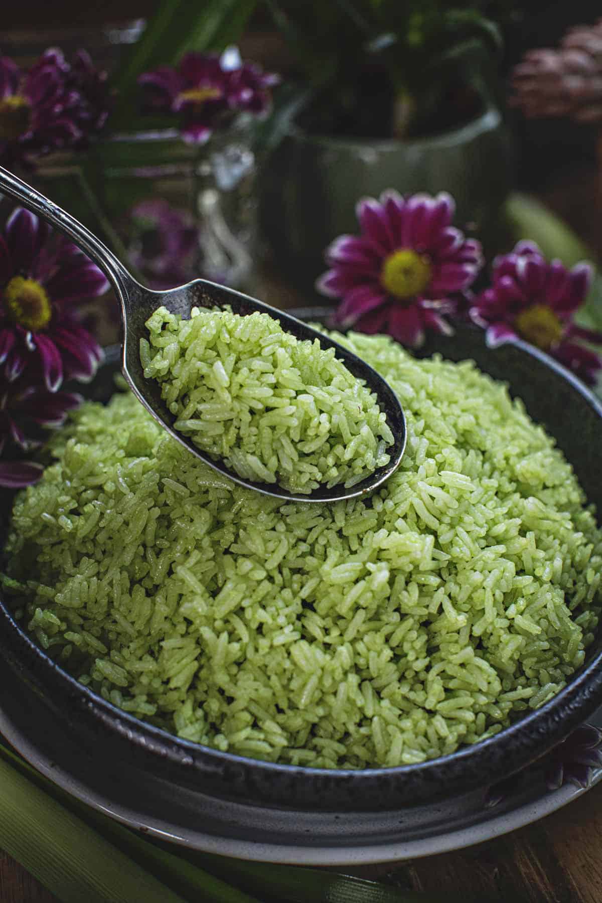 A spoon lifting green rice from a bowl. 