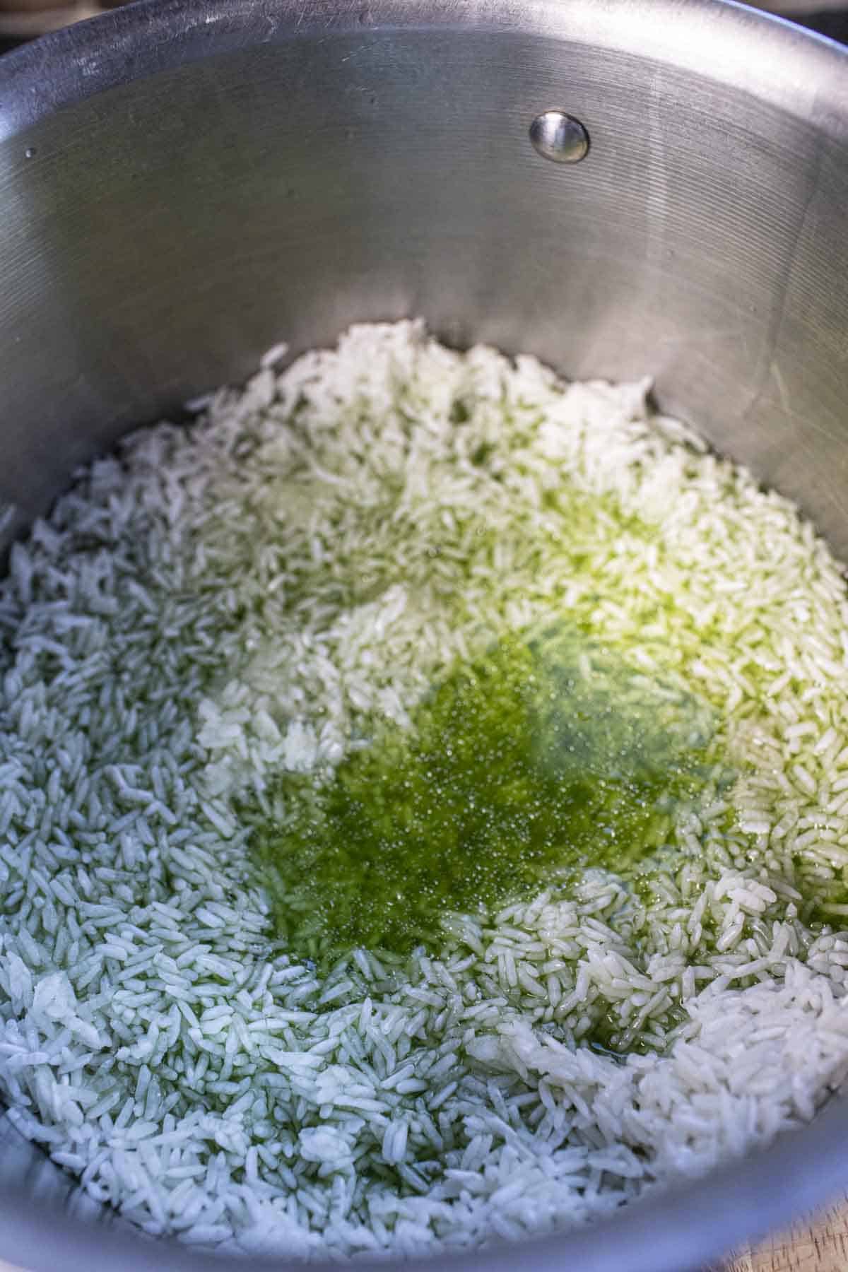 Rice grains with green pandan water in a pot. 