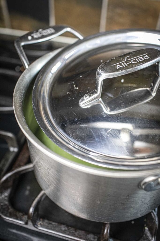 Green rice in a pot with lid on the stove.