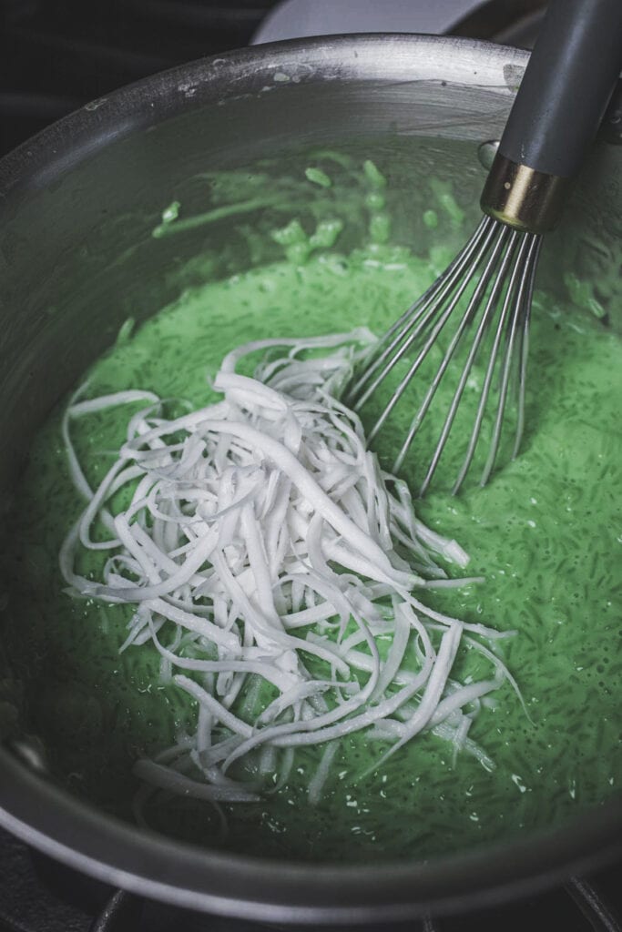 Shredded coconut and green pandan juice in a sauce pan.