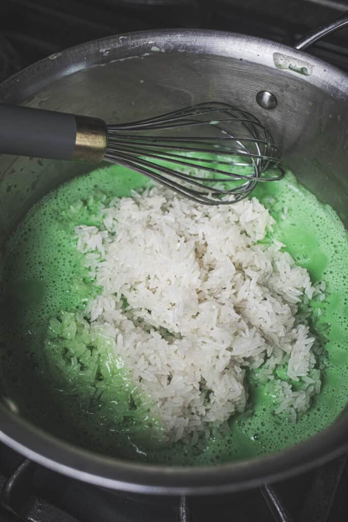 Sticky rice and green pandan juice in a sauce pan.