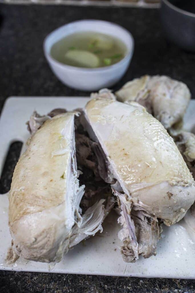 Sliced in half cooked whole chicken on a cutting board. 