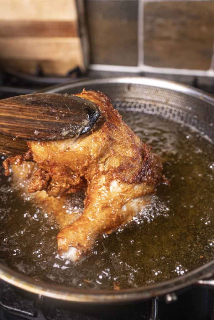 Fried chicken in hot oil on the stove.