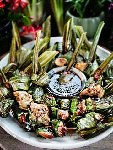 Thai pandan chicen in wrapped pandan leaves on a plate.