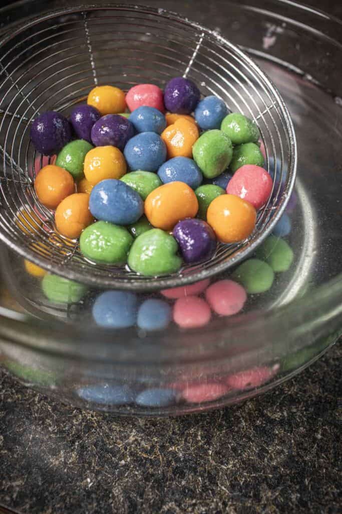 Slotted spoon lifting Colorful Bua Loy pearls from a bowl. 