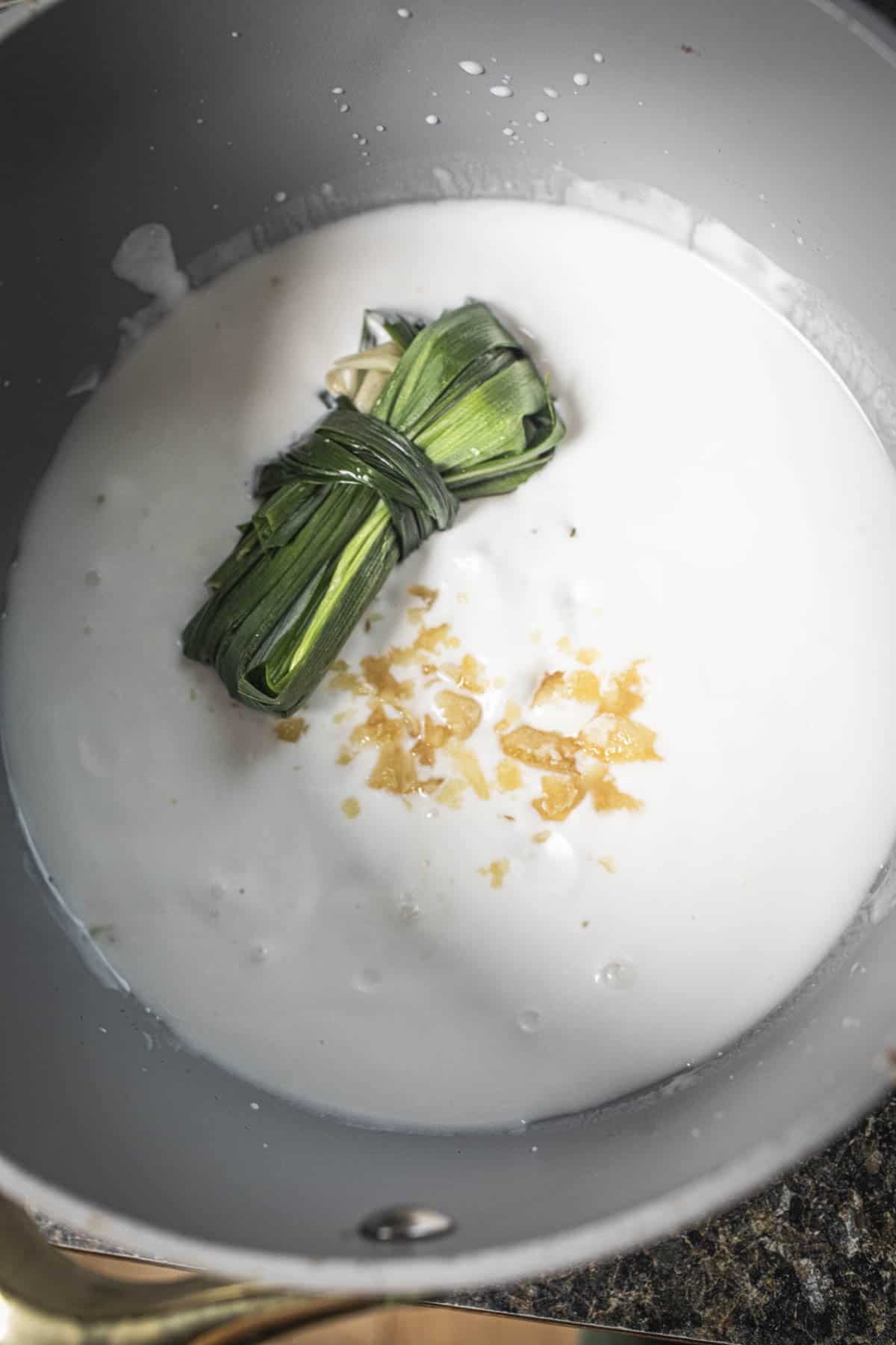 pandan leaves and palm sugar in coconut milk in a pot. 