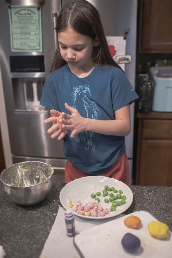 Little girl rolling tapioca pearls on the counter. 