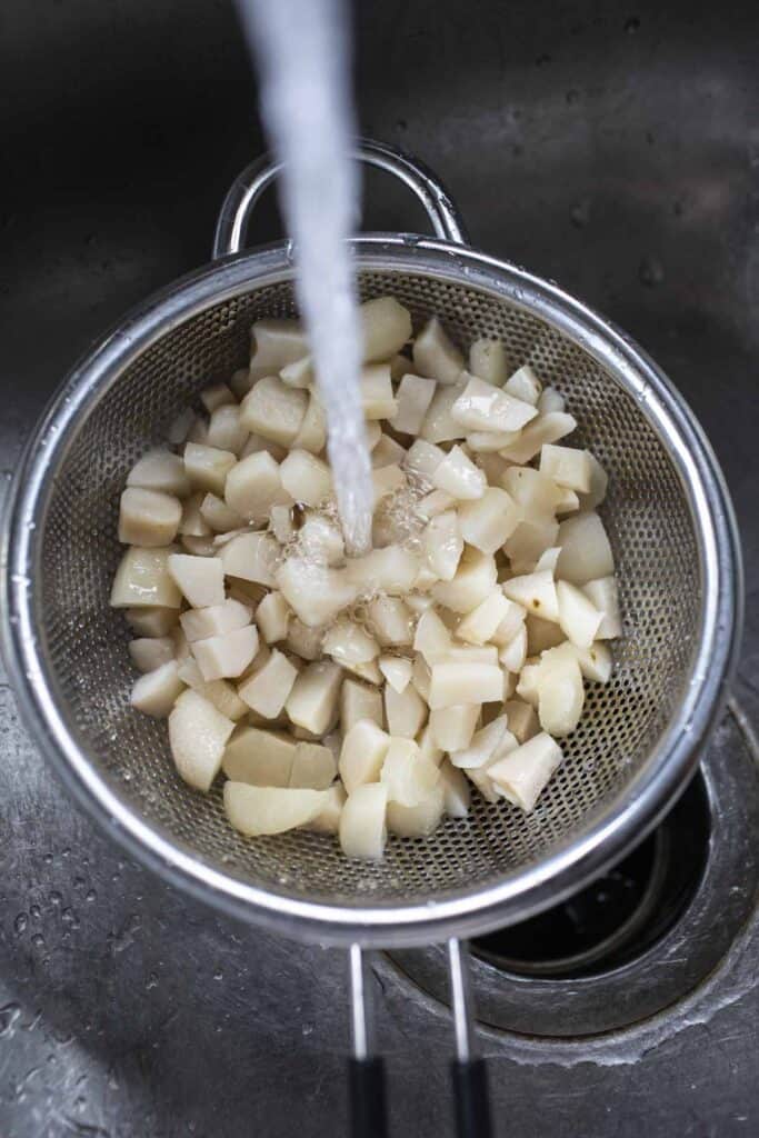 Water rinsing diced water chesnuts in a colander. 