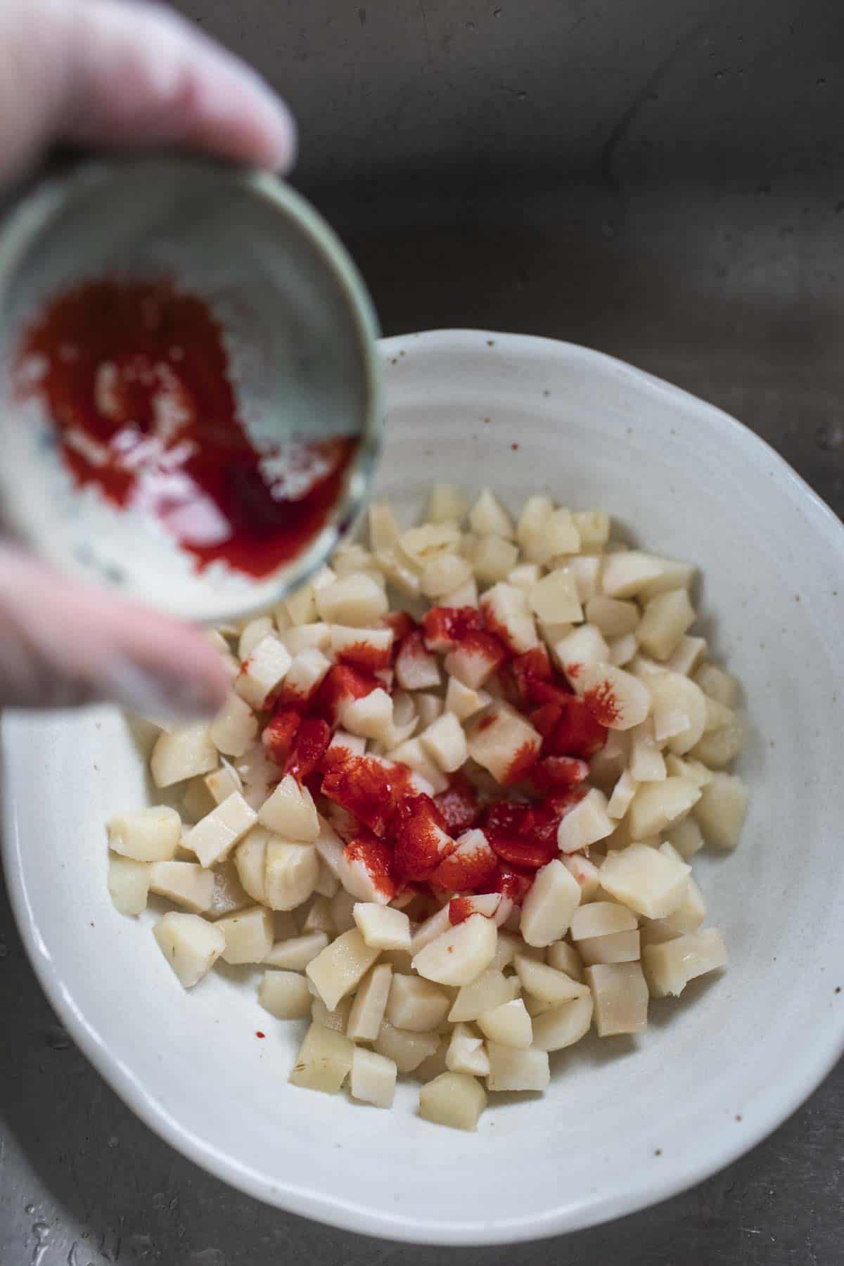Red food coloring in a bowl with diced waterchesnuts. 