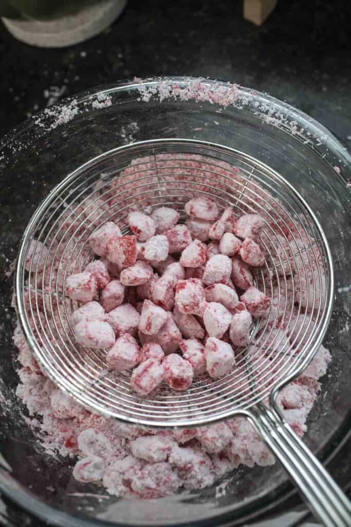 Tapioca flour coated Red waterchestnuts pearls in a wiremesh strainer. 