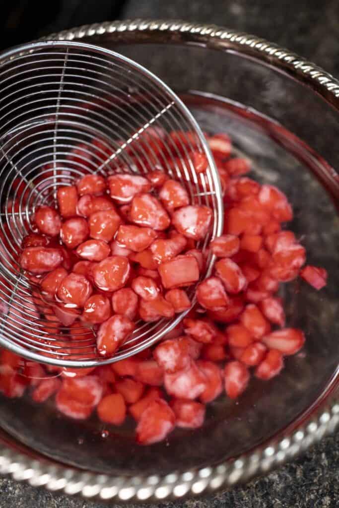 Wire mesh strainer lifting Red water chestnut pearls.