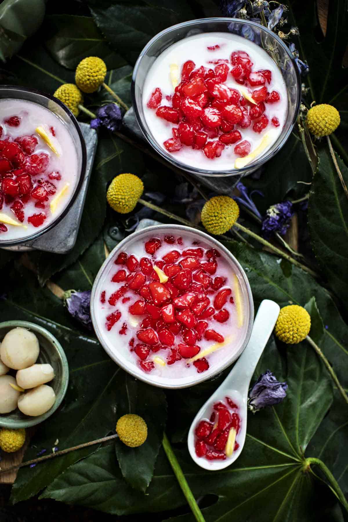 Thai red rubies dessert in a bowl with flowers around. 