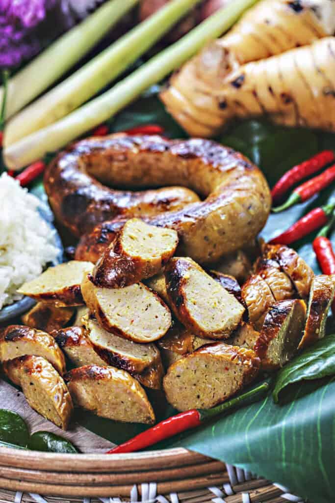 Sliced and whole sausage on a platter with herbs. 
