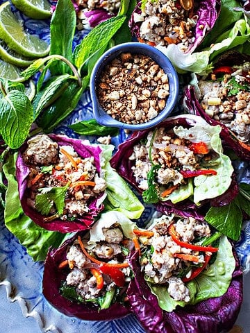 Pork lettuce wraps on a tray with peanuts in the middle.