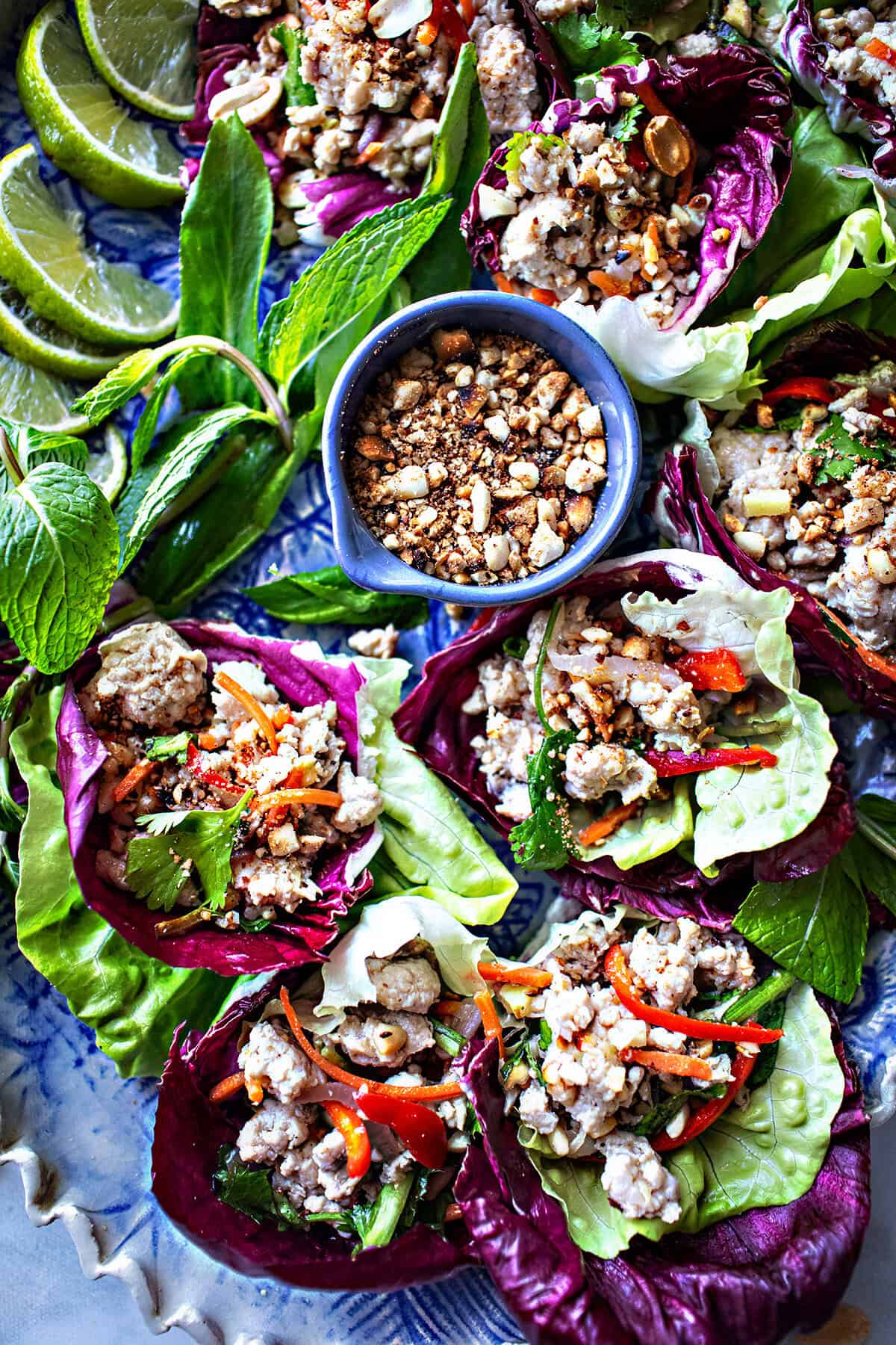 Thai lettuce wraps on a platter with a bowl of peanuts inthe middles.