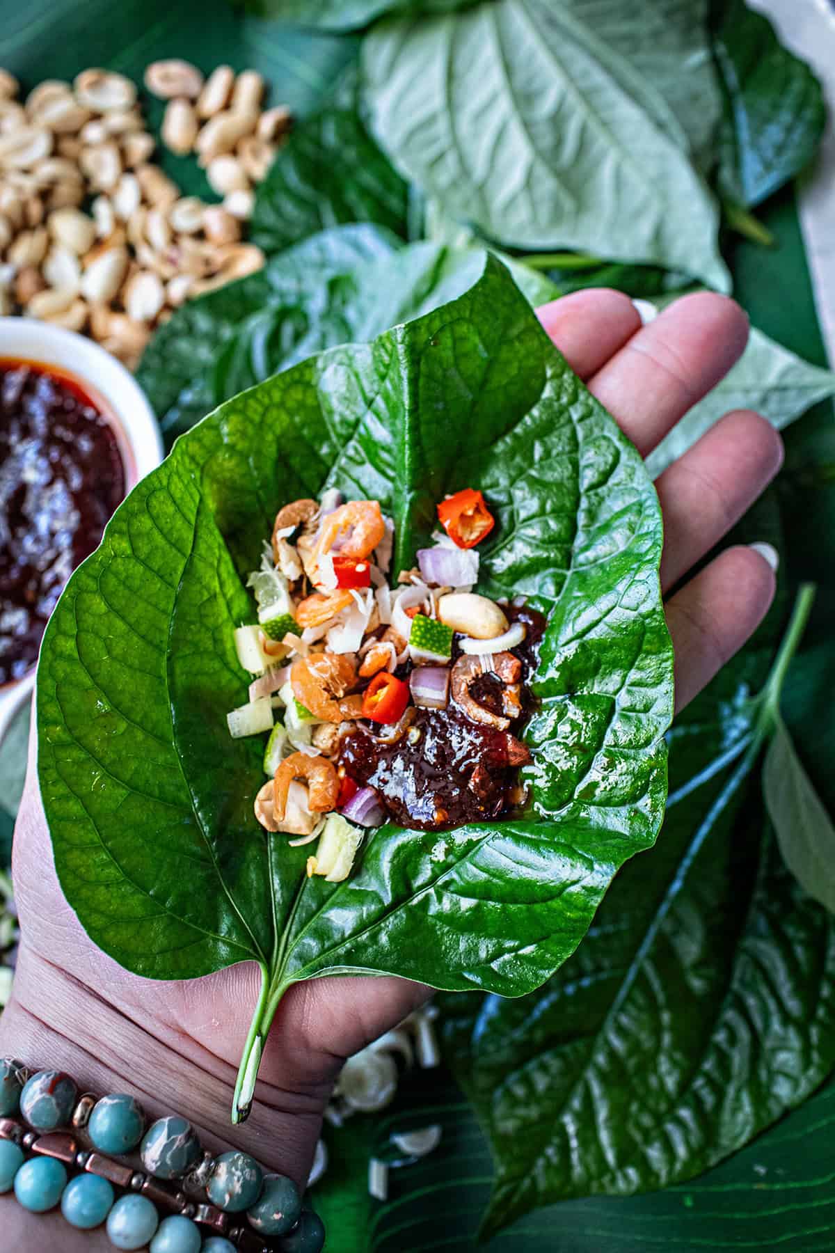 Hand holding Ingredients for Miang Kham wrap.