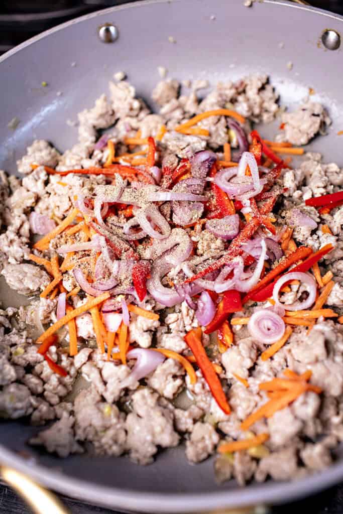 Thai ground pork with vegetables in a pan on the stove. 