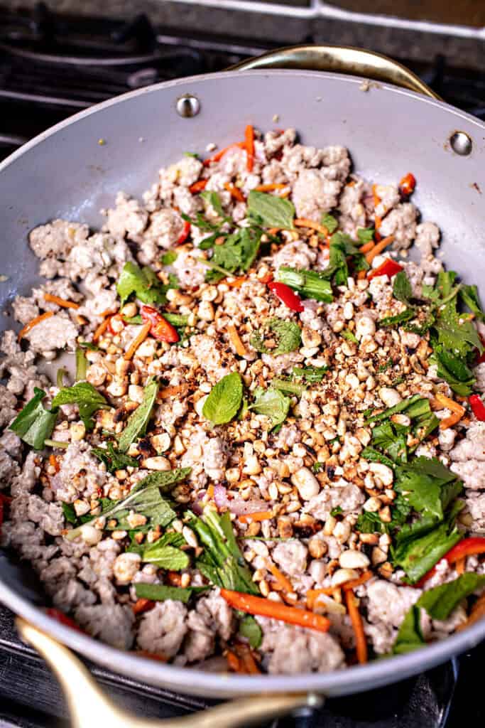 Thai pork salad with herbs in a pan on the stove. 