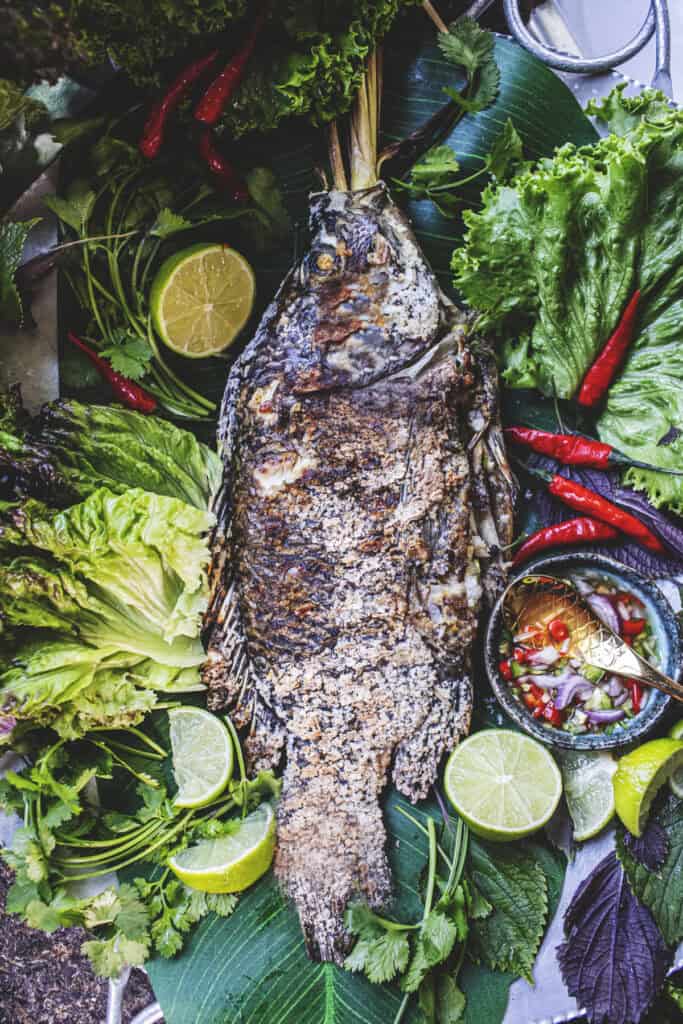 Salted whole fish on a tray with dipping sauce.