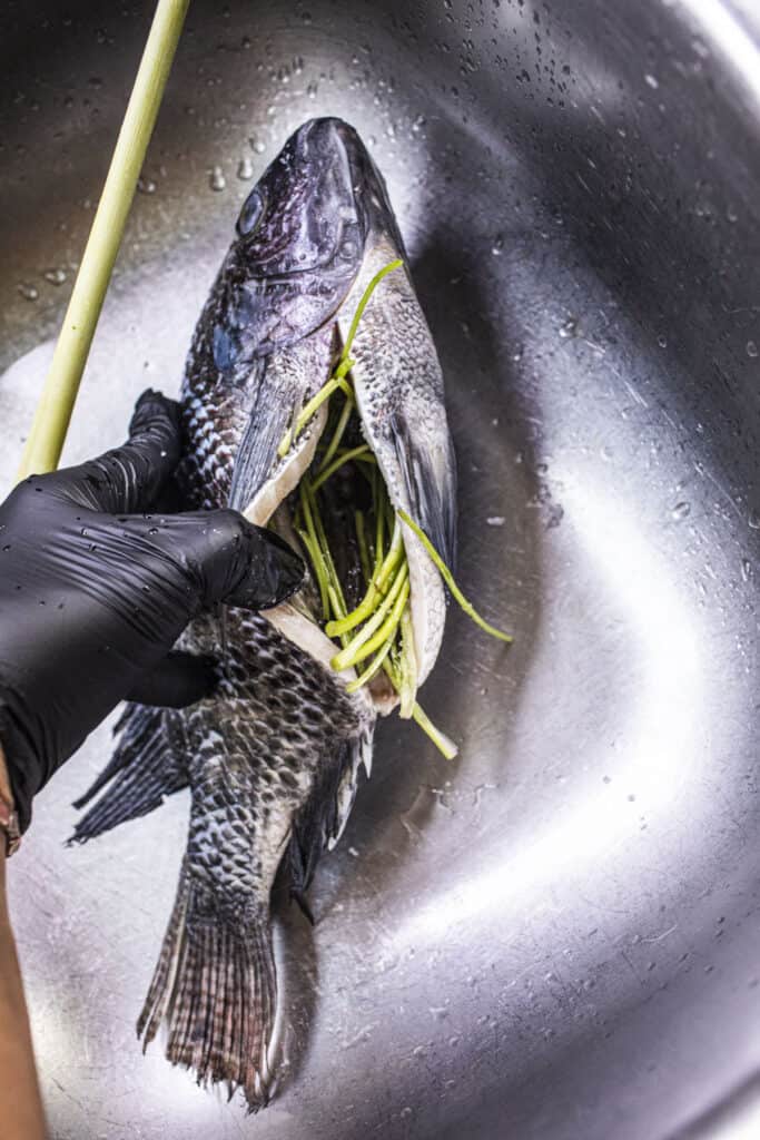 Whole fish with stuffed herbs in a sink.