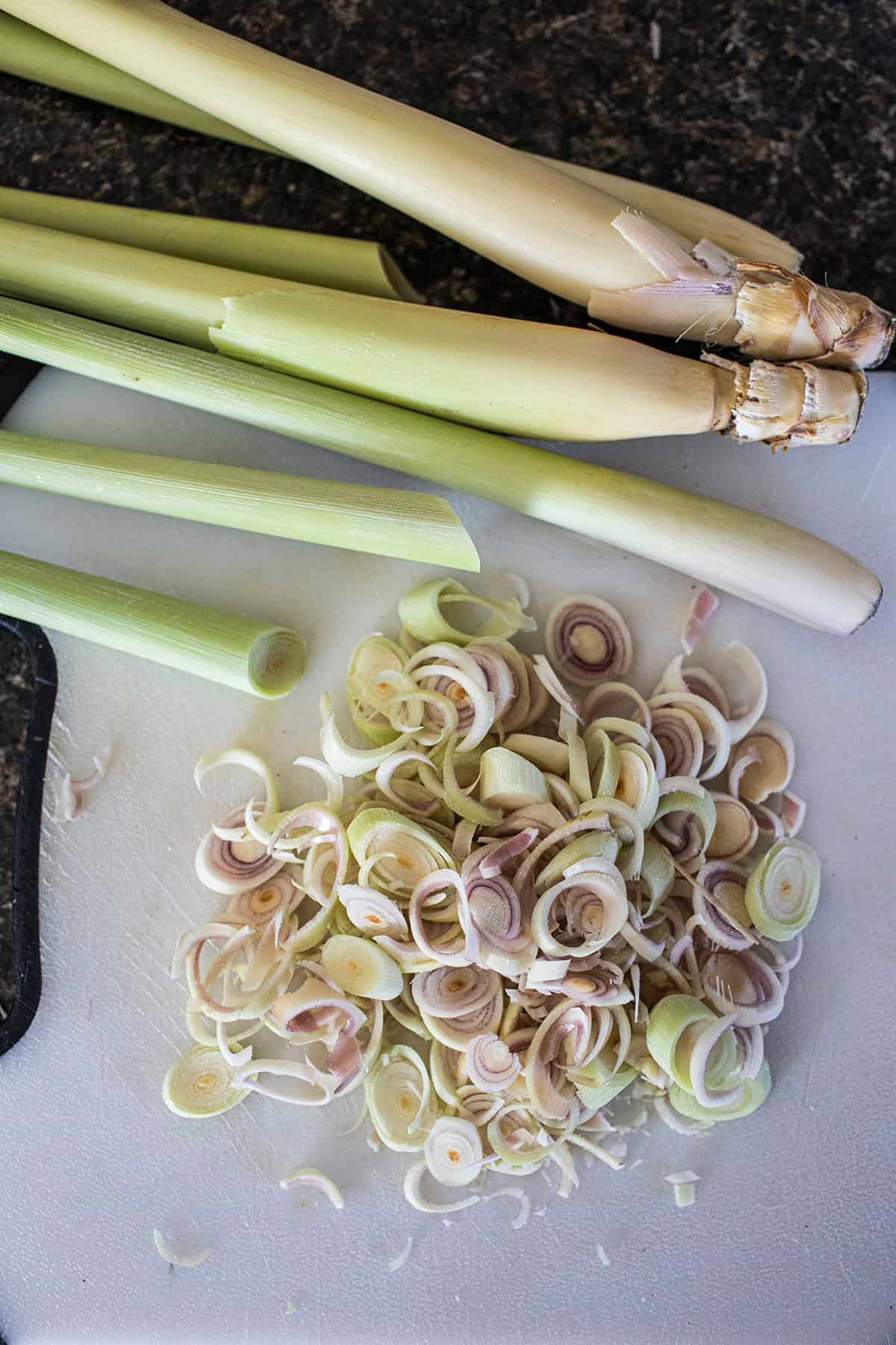 Thinly sliced lemongrass on a cutting board.