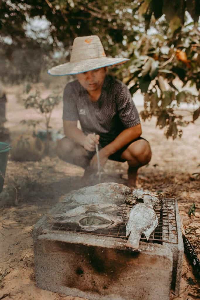 A thai man in Isaan grilling Pla pao.