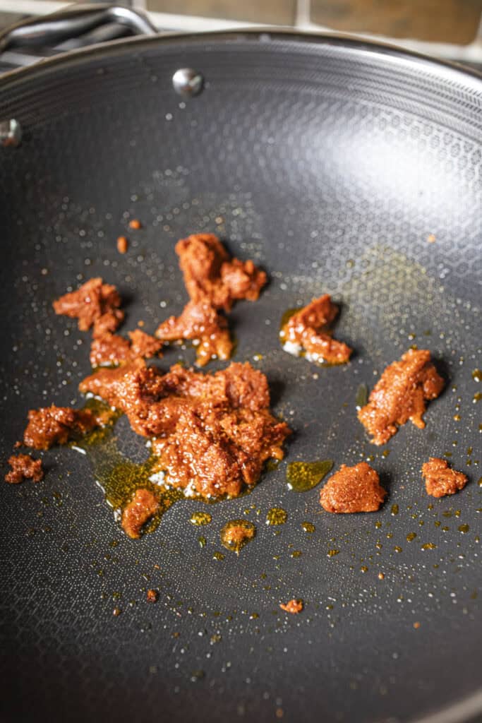 Red curry paste frying in a wok. 