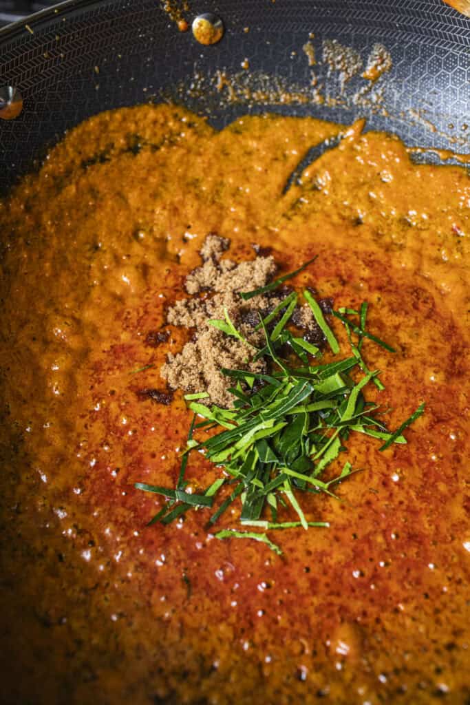 red curry sauce with sliced kaffir leaves and sugar. 